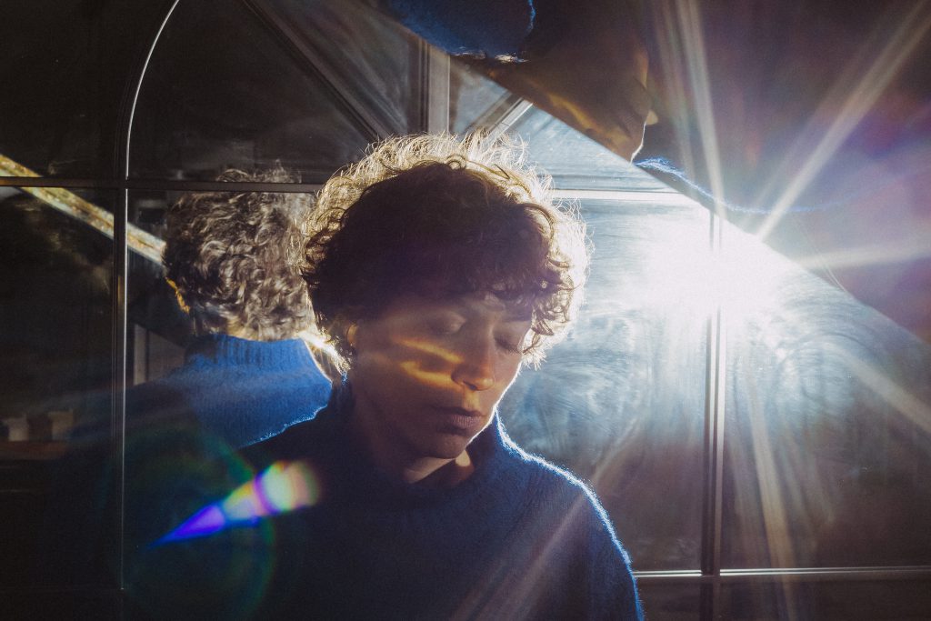 Frau vor einer Glasscheibe, durch die ein helles Licht scheint