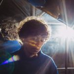 Frau vor einer Glasscheibe, durch die ein helles Licht scheint