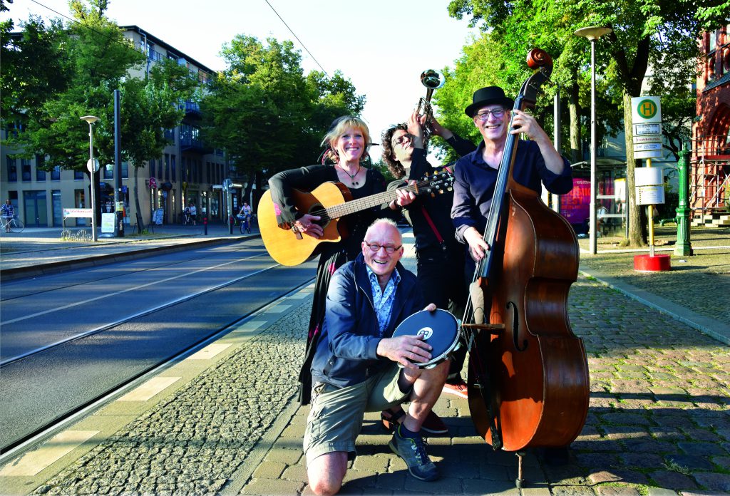 Musiker mit Gitarre und Kontrabass stehen auf dem Gehweg an einer Straße