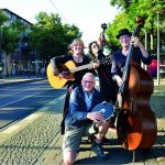 Musiker mit Gitarre und Kontrabass stehen auf dem Gehweg an einer Straße