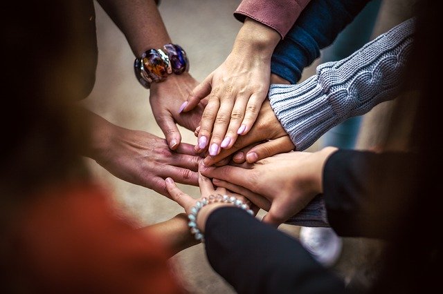Menschen legen ihre Hände im Kreis stehend mittig aufeinander